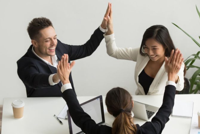 Excited multiracial team holding hands giving high five celebrating success